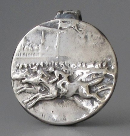 “Ahead By A Nose” 1" diameter, Price: $189, Chisholm Ref. #: S-SH2 - This silver piece captures the excitement of a close horse race. Horses and jockeys vie for position in the foreground. Behind them spectators crowd the rail with the grandstand rising in the background. Handcrafted in .960 silver.