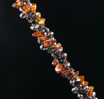 Irene Greenberg “Ambling Along Silver & Beadwork Necklace” Pendant: 1.5" square, Overall length: 18", Price: $650, Chisholm Ref #: SBW-N1 - This one-of-a-kind, beaded necklace is made of amber, freshwater pearls, fire polished Czech crystals, and Japanese square & ring shaped glass beads. The handmade silver bead caps show the imprint of many warmblood breed logos. The focal piece is a hand-painted, fused glass pendant featuring a relaxed rider ambling along.