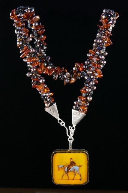 “Ambling Along Silver & Beadwork Necklace” Pendant: 1.5" square, Overall length: 18", Price: $650, Chisholm Ref #: SBW-N1 - This one-of-a-kind, beaded necklace is made of amber, freshwater pearls, fire polished Czech crystals, and Japanese square & ring shaped glass beads. The handmade silver bead caps show the imprint of many warmblood breed logos. The focal piece is a hand-painted, fused glass pendant featuring a relaxed rider ambling along.