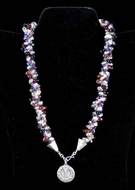 “Cabernet Horseshoe Beaded Necklace” Overall length: 19.25", Pendant diameter: 7/8", Price: $550, Chisholm Ref. #: SBW-N2 | One-of-a-kind silver & beadwork necklace is woven with clear quartz crystal beads, Czech fire polished crystals, a colorful blend of square Japanese glass beads, and teardrop shaped glass beads in a rich wine color. The end-caps are textured with warm blood breed logos, and the focal piece is a horseshoe as seen from the farrier's point of view. The findings are all handcrafted in .960 silver.