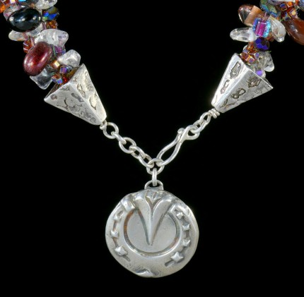 “Cabernet Horseshoe Beaded Necklace” Overall length: 19.25", Pendant diameter: 7/8", Price: $550, Chisholm Ref. #: SBW-N2 | One-of-a-kind silver & beadwork necklace is woven with clear quartz crystal beads, Czech fire polished crystals, a colorful blend of square Japanese glass beads, and teardrop shaped glass beads in a rich wine color. The end-caps are textured with warm blood breed logos, and the focal piece is a horseshoe as seen from the farrier's point of view. The findings are all handcrafted in .960 silver.