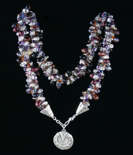 “Cabernet Horseshoe Beaded Necklace” Overall length: 19.25", Pendant diameter: 7/8", Price: $550, Chisholm Ref. #: SBW-N2 | One-of-a-kind silver & beadwork necklace is woven with clear quartz crystal beads, Czech fire polished crystals, a colorful blend of square Japanese glass beads, and teardrop shaped glass beads in a rich wine color. The end-caps are textured with warm blood breed logos, and the focal piece is a horseshoe as seen from the farrier's point of view. The findings are all handcrafted in .960 silver.