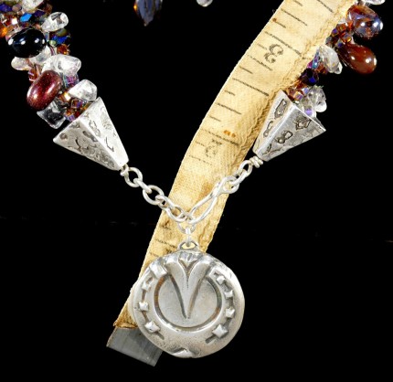 “Cabernet Horseshoe Beaded Necklace” Overall length: 19.25", Pendant diameter: 7/8", Price: $550, Chisholm Ref. #: SBW-N2 | One-of-a-kind silver & beadwork necklace is woven with clear quartz crystal beads, Czech fire polished crystals, a colorful blend of square Japanese glass beads, and teardrop shaped glass beads in a rich wine color. The end-caps are textured with warm blood breed logos, and the focal piece is a horseshoe as seen from the farrier's point of view. The findings are all handcrafted in .960 silver.