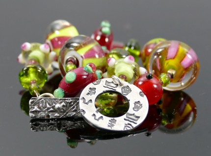 “Glowing Glass Bracelet” Overall length: 8.5", Price: $229, Chisholm Ref. #: SB-111 | One of a kind bracelet made with brilliant, lamp-worked, glass beads, vintage crystal, and glass seed beads. The round toggle clasp bears the logos of the major warmblood breeds. Findings handcrafted in .960 silver.