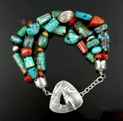 “Ocean Inspiration Bracelet” Overall length: 8", Price: $329, Chisholm Ref. #: SB-111 | One of a kind beaded bracelet made with three strands of turquoise, red coral, silver, and antique trade beads. The end caps are sterling silver, machine handmade. The large handmade clasp shows a mesmerizing wave pattern which is perfectly paired with a seashell shaped closure. Clasp handcrafted in .960 silver.