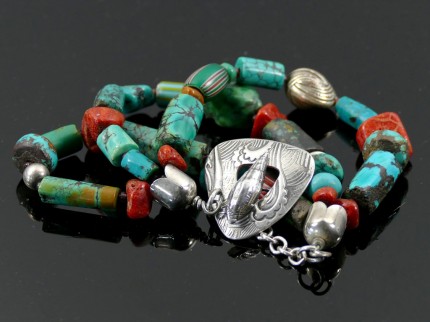 “Ocean Inspiration Bracelet” Overall length: 8", Price: $329, Chisholm Ref. #: SB-111 | One of a kind beaded bracelet made with three strands of turquoise, red coral, silver, and antique trade beads. The end caps are sterling silver, machine handmade. The large handmade clasp shows a mesmerizing wave pattern which is perfectly paired with a seashell shaped closure. Clasp handcrafted in .960 silver.