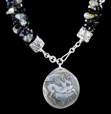 “Pegasus Blue Glow Silver & Beadwork Necklace” Pendant: 1.25" diameter, Overall length: 21", Price: $650, Chisholm Ref. #:SBW-N7 - This one-of-a-kind silver & beadwork necklace is made of labradorite, jet, and Czech fire polished crystals. The handmade silver end-caps are deeply textured. The focal piece of the necklace is a large, Pegasus pendant modeled on a Greek coin. The reverse of the pendant is impressed with the pattern of a real feather. Handcrafted in .960 silver.
