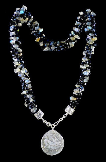 “Pegasus Blue Glow Silver & Beadwork Necklace” Pendant: 1.25" diameter, Overall length: 21", Price: $650, Chisholm Ref. #:SBW-N7 - This one-of-a-kind silver & beadwork necklace is made of labradorite, jet, and Czech fire polished crystals. The handmade silver end-caps are deeply textured. The focal piece of the necklace is a large, Pegasus pendant modeled on a Greek coin. The reverse of the pendant is impressed with the pattern of a real feather. Handcrafted in .960 silver.