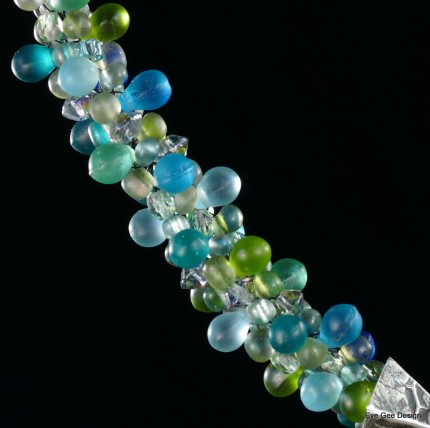 “Seafoam Polo Necklace” Overall length: 16", Polo pendant: 7/8" Diameter, Price: $550, Chisholm Ref. #: SBW-N10 | This one-of-a-kind silver & beadwork necklace is woven of glass beads: matte teardrops, Czech fire polished crystals, and seed bead, all in hues of the brilliant ocean. The silver end-caps are textured with wildflower leaves, and the focal piece features a polo player & pony both totally intent on the ball. The findings are all handcrafted in .960 silver.