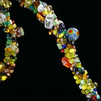 “Spirited Dressage Beaded Necklace” Overall length: 20", Clasp length: 2", Price: $550, Chisholm Ref. #: SBW-N9 | One-of-a-kind silver & beadwork necklace is woven using a multicolored “bead soup” made up of glass beads of many shapes and sizes. The end-caps are textured with many of the warm blood breed logos. The textured clasp declares, “Dressage,” while providing support for an asymmetrical tassel of beads. The findings are all handcrafted in .960 silver.