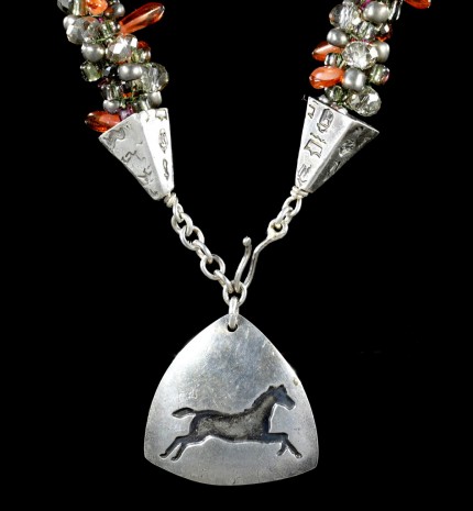 “Triple Luck Beaded Necklace” Overall length: 19", Pendant: 1.25" x 1.25", Price: $550, Chisholm Ref. #: SBW-N11 | One-of-a-kind silver & beadwork necklace made of freshwater pearls, Czech fire polished crystals, Czech glass dagger beads, and glass seed beads. The handmade, silver end-caps are textured with a motif of warmblood breed logos. The focal piece of the necklace is a convex, triangular pendant with the dramatic silhouette of a running horse. The findings are all handcrafted in .960 silver.