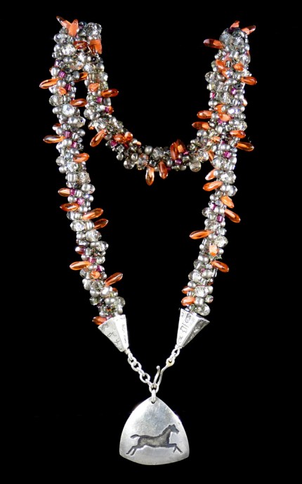 “Triple Luck Beaded Necklace” Overall length: 19", Pendant: 1.25" x 1.25", Price: $550, Chisholm Ref. #: SBW-N11 | One-of-a-kind silver & beadwork necklace made of freshwater pearls, Czech fire polished crystals, Czech glass dagger beads, and glass seed beads. The handmade, silver end-caps are textured with a motif of warmblood breed logos. The focal piece of the necklace is a convex, triangular pendant with the dramatic silhouette of a running horse. The findings are all handcrafted in .960 silver.